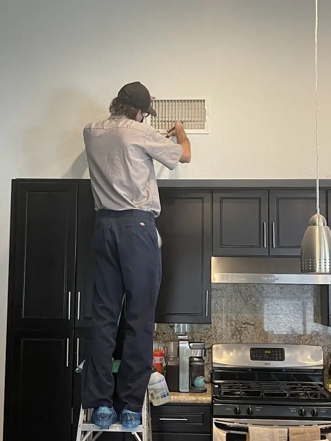 Technician inspecting an air vent during HVAC service in Nampa
